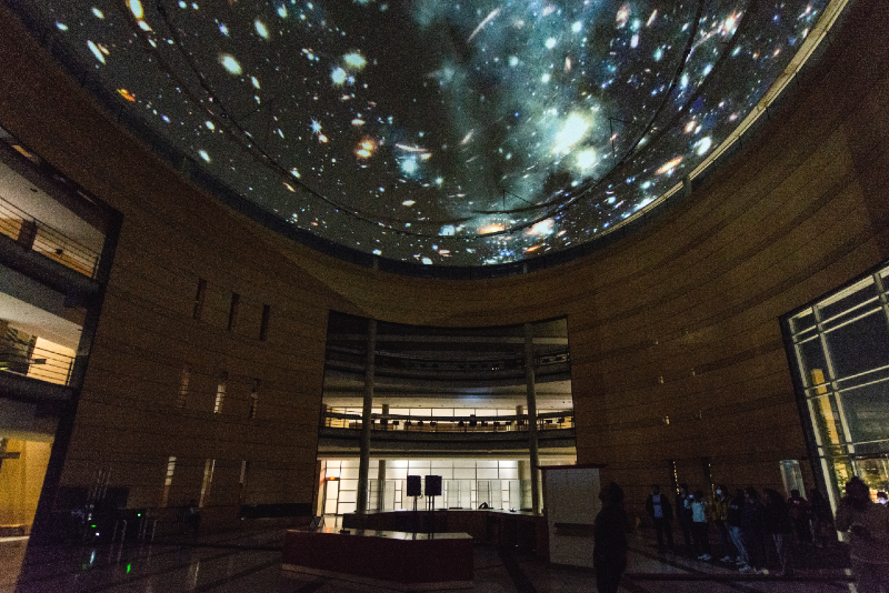 A colour photograph of a domed ceiling at night with a digital projection of a starry night sky shown on top of it.