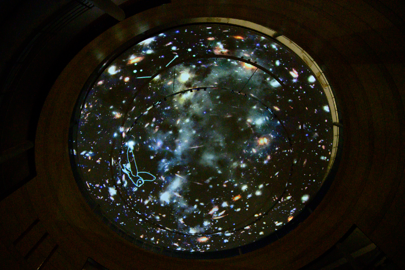 A colour photograph of a domed ceiling at night with a digital projection of a starry night sky shown on top of it.