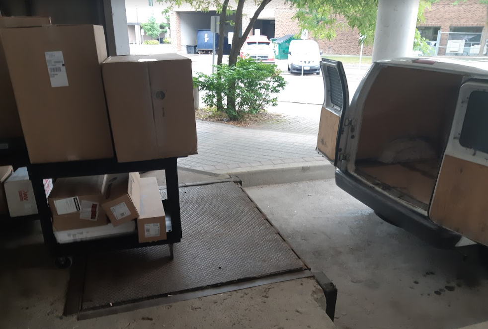 A photograph of a moving van and a bunch of cardboard boxes inside of an industrial loading dock.