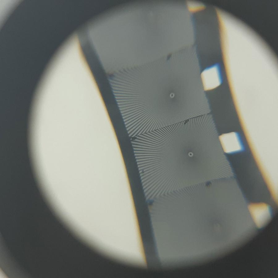 A photograph of a section of film reel as seen through a magnifying glass.