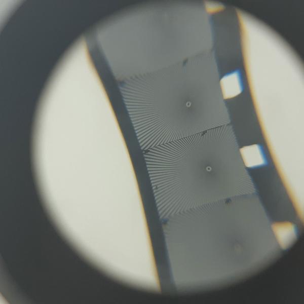 A photograph of a section of film reel as seen through a magnifying glass.